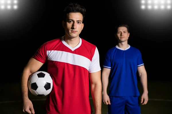职业足球运动员举行球与对手球员站立在后面在橄榄球场 — 图库照片