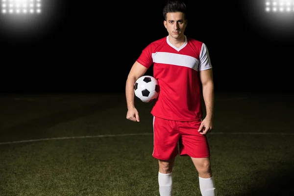 身着红白相间制服的年轻足球运动员的肖像站在运动场上 眼神交流 — 图库照片