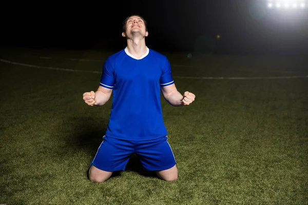 足球运动员在他的膝盖上抬起拳头和庆祝后 在球场上的目标 — 图库照片