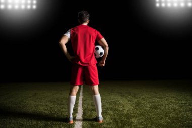 Kırmızı mayoyu futbol sahada topu ile ayakta futbolcu tam uzunlukta