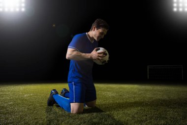 Genç futbolcu bir futbol gol gol sonra tutarak diz