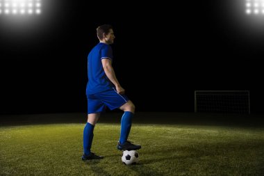 Tam uzunlukta futbolcu ayağı ile yere bir futbol topu yere tutuyoruz