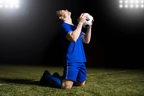 Jogador Futebol Comemorando Gol Com Bola Mão Joelho Deslizar Estádio — Fotografia de Stock