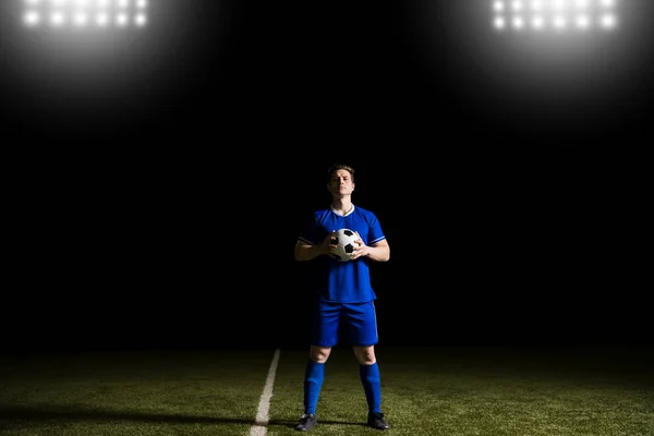 足球运动员穿着蓝色制服站在足球场上 握着一个球 并进行眼神交流 — 图库照片