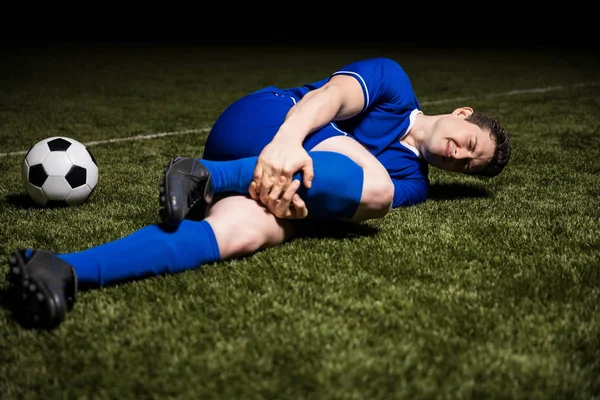 足球运动员在足球比赛中躺在球场上腿部受伤 — 图库照片