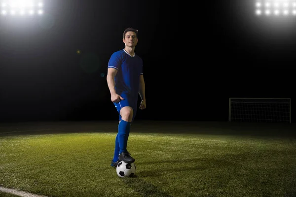 全长肖像的职业青年足球运动员在蓝色制服站在足球场上足球球 — 图库照片