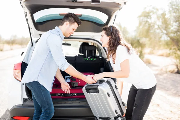 Young man and woman loading their bags in car trunk