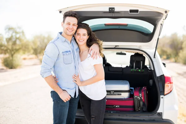 男子和妇女微笑着站在汽车与行李在树干 — 图库照片