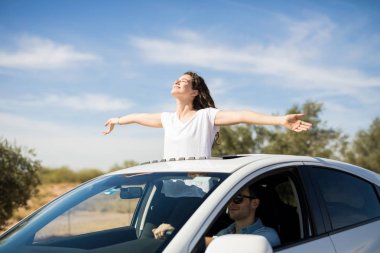 woman standing out of sunroof with arms outstretched clipart