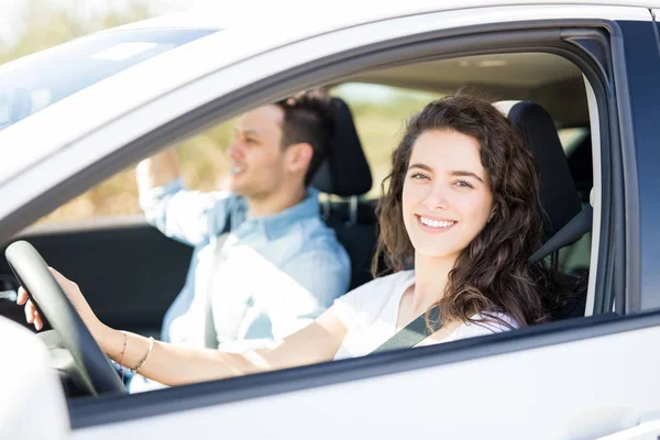 若い女性が助手席に座っている人で車を運転 — ストック写真