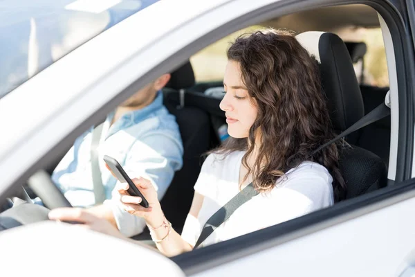 Jovem Mulher Usando Smartphone Enquanto Dirige Carro Com Namorado — Fotografia de Stock