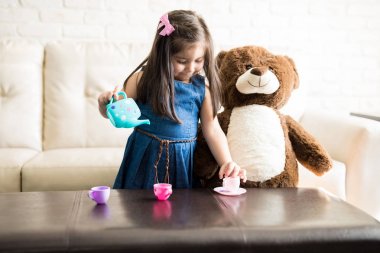 çay çay seti kullanarak partide oyuncak ayı ile oynayan kız