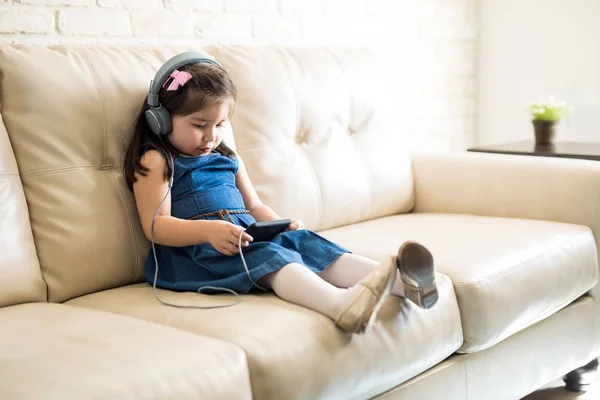 Little Girl Sitting Sofa Headphones Watching Movie Smartphone — Stock Photo, Image