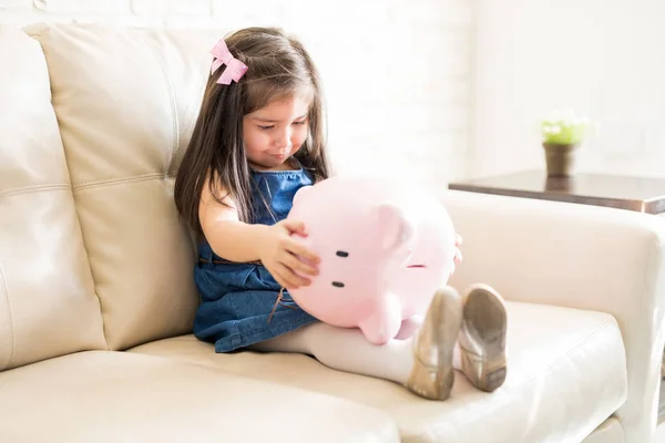Kleines Mädchen Sitzt Auf Sofa Und Hält Sparschwein — Stockfoto