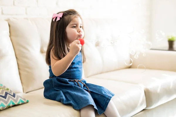 Little Girl Sitting Sofa Blowing Soap Bubbles Living Room — Stock Photo, Image