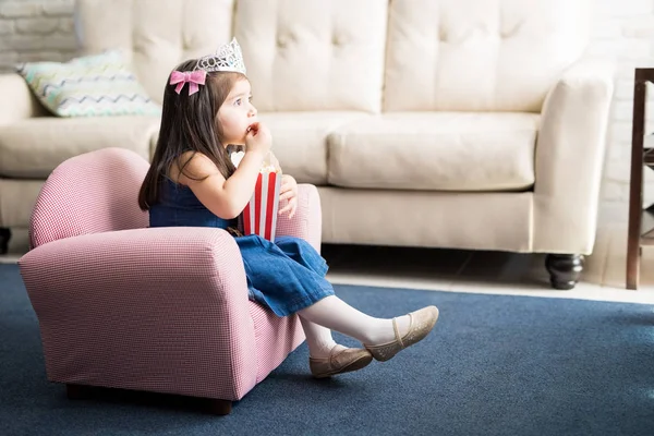 公主皇冠上的女孩看电影和在家吃爆米花 — 图库照片