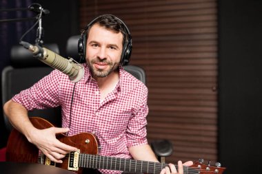 gitar çalmak ve radyo istasyonu mikrofon şarkı genç erkek şarkıcı