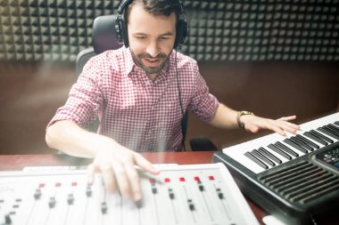 müzikal klavye ile çalışma ve ses yalıtımlı kayıt stüdyosu panelinde karıştırma ses mühendisi