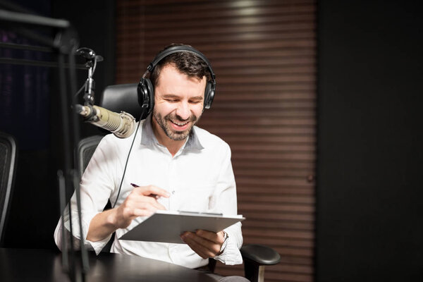 Portrait of young male radio host at radio station with headphones and microphone