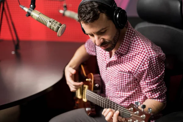 ライブ ラジオ局に座って歌いながらギターを弾く男性ギタリスト — ストック写真