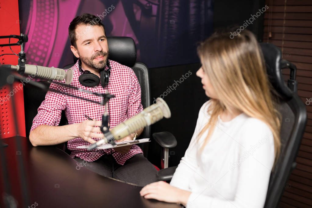 Male radio presenter hosting an interview with famous woman at radio station