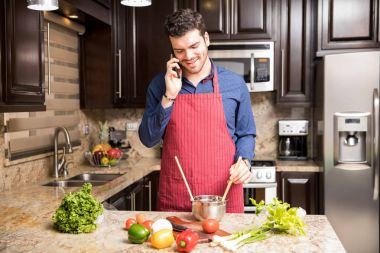 Cep telefonundan konuşuyor ve yemek yemek mutfakta yakışıklı genç İspanyol adam