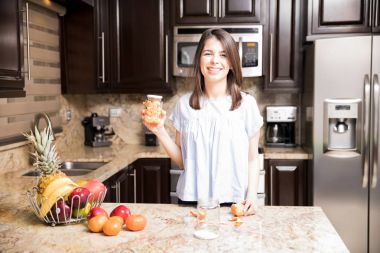 Mutfakta ayrılmış portakal bölümleri ile bir şişe tutan çekici genç kadın portresi