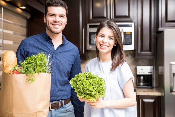 買い物袋と新鮮な野菜を台所に一緒に美しいラテン カップル立っています — ストック写真
