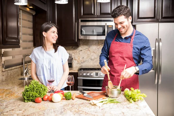 Uśmiechnięty Mężczyzna Hiszpanie Mieszania Warzyw Misce Swoją Dziewczyną Stojących Kuchni — Zdjęcie stockowe