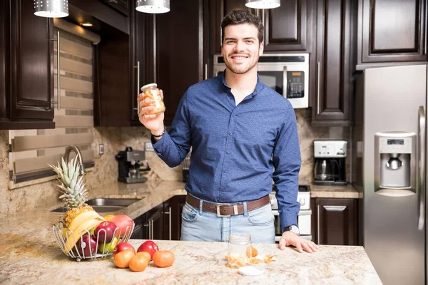 Портрет Симпатичного Латиноамериканца Держащего Бутылку Оранжевыми Порциями Кухне — стоковое фото