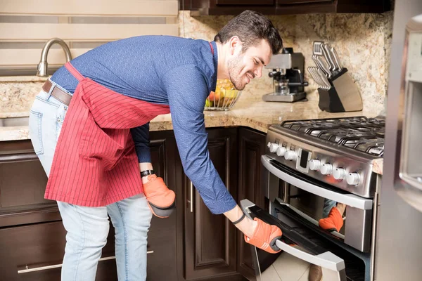 Happy Young Hispanic Man Wearing Apron Oven Mitts Opening Oven — Stock Photo, Image