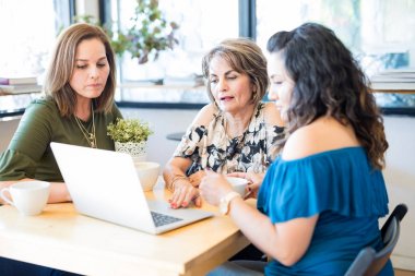Çekici İspanyol orta yaşlı kadın bir şey kahve dükkanında arkadaşlarına dizüstü bilgisayarda gösterme