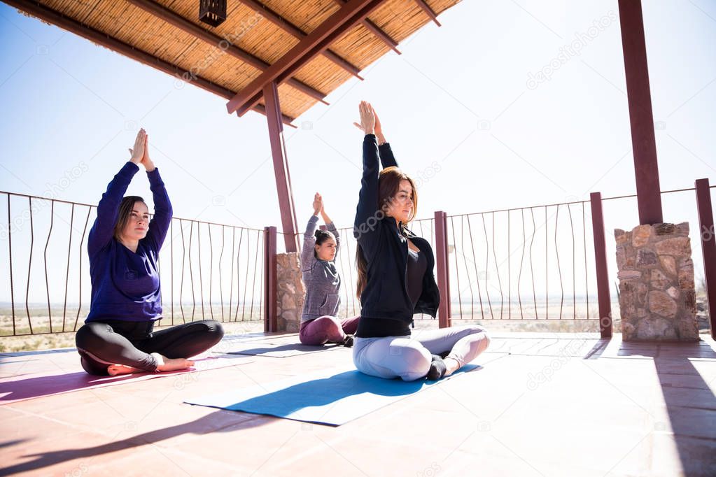 Group of three Hispanic women relaxing in a easy yoga pose at yoga class