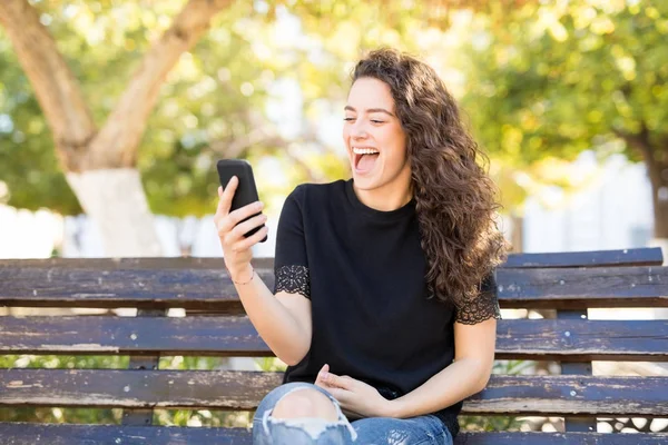 Joven Mujer Emocionada Sentada Banco Haciendo Una Videollamada Con Teléfono —  Fotos de Stock