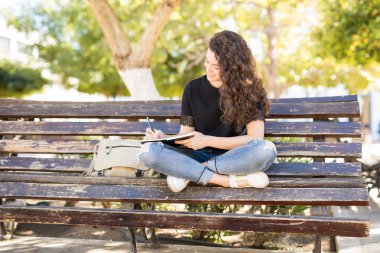 Bir bankta oturan ve bir günlüğüne yazma genç kadın