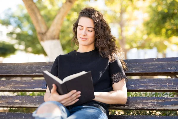 公園のベンチでリラックスして本を読んで 代の豪華な女性 — ストック写真