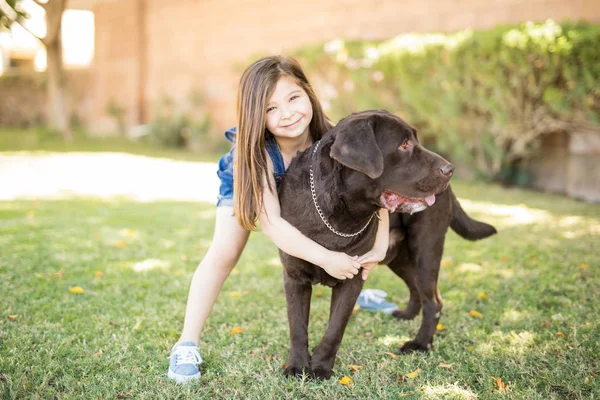 Sorrindo Criança Pequena Abraçando Labrador Chocolate Fora Casa — Fotografia de Stock