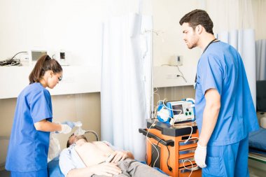 Acil durum odasında baygın bir hasta üzerinde erkek ve kadın doktorlar