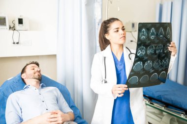 Güzel genç hastane acil servise yatakta yatan bir erkek hasta muayene Ct taraması sonuçlarını doktor