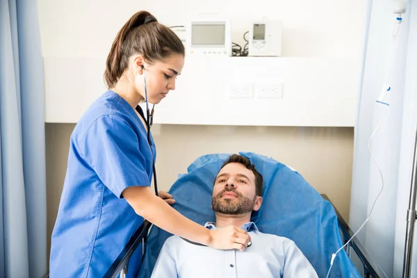 Vacker Sjuksköterska Med Ett Stetoskop För Att Undersöka Manlig Patient — Stockfoto