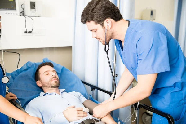 Junge Ärzte Untersuchen Einen Männlichen Patienten Und Überprüfen Seinen Blutdruck — Stockfoto