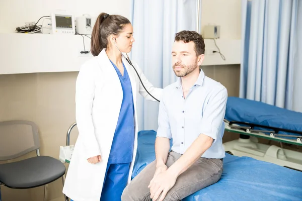 Schöne Junge Lateinamerikanische Ärztin Überprüft Männlichen Patienten Mit Stethoskop Krankenhauszimmer — Stockfoto