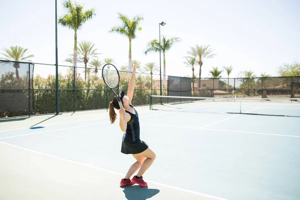 适合年轻女子网球运动员发球 同时在球场上练习 — 图库照片