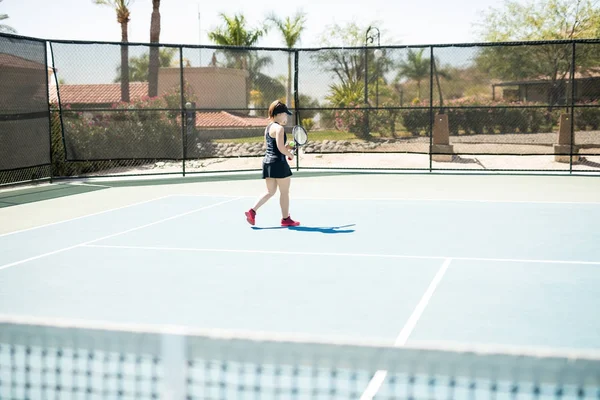 ボールとラケット テニス コートでベース ラインに向かって歩いスポーツウェアの若い女性 — ストック写真