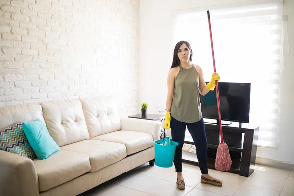 Frustrated woman feeling tired cleaning home with broom