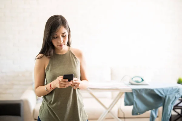 Mujer Despreocupada Usando Teléfono Móvil Olvidando Hierro Tabla Planchar — Foto de Stock