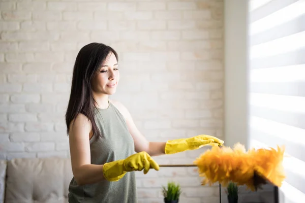 Young Woman Dusting Television Top Wearing Yellow Gloves Orange Duster — Stock Photo, Image