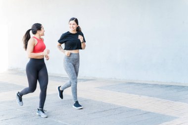 Yürüme yolunda birlikte koşan gülümseyen genç kadınlarla dolu.