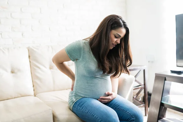 Piękna Kobieta Ciąży Cierpiąca Bóle Pleców Siedząc Kanapie Podczas Ciąży — Zdjęcie stockowe