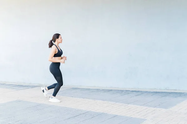 Widok Boku Kaukaska Kobieta Sportowiec Jogging Przez Ścianę Chodniku — Zdjęcie stockowe